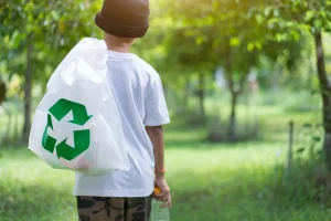 Dziecko chodzi z workami na śmieci, wśród zielonego lasu, dbając o środowisko, przestrzeń do kopiowania